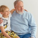 A grandfather and grandson sitting together, smiling and sharing a joyful moment.