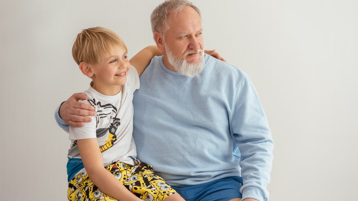 A grandfather and grandson sitting together, smiling and sharing a joyful moment.